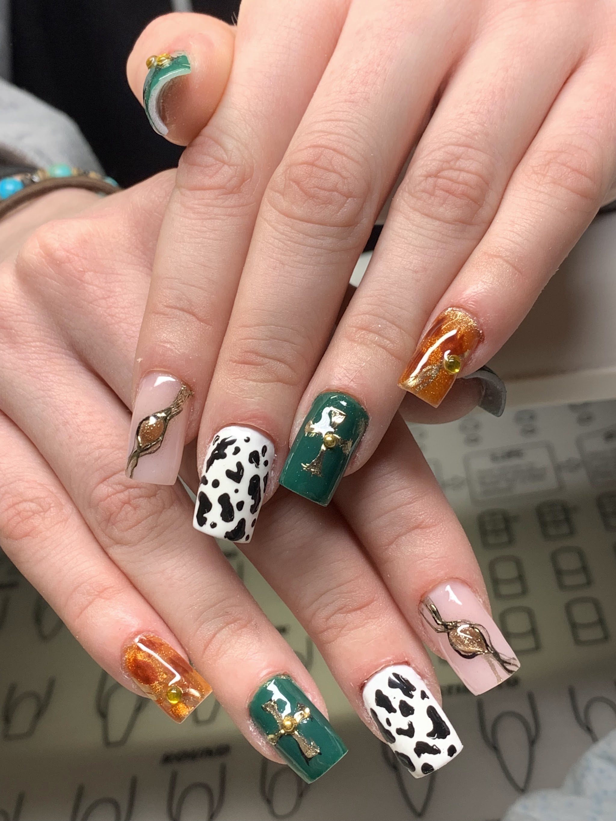 Nail art met koeienprint en gouden kruis